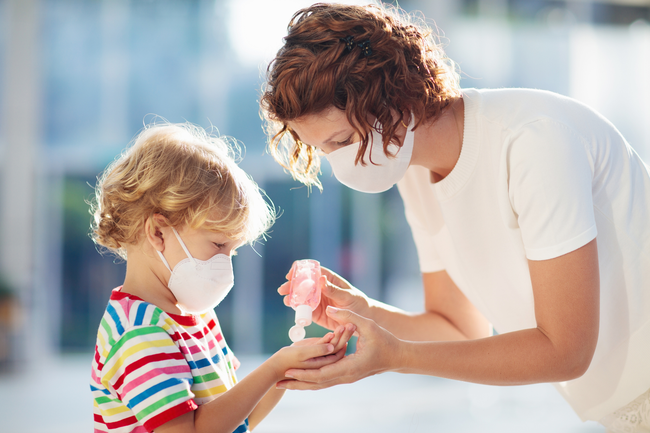 Cosmetic Services - mother putting hand sanitizer on her sons hands, both are wearing a mask