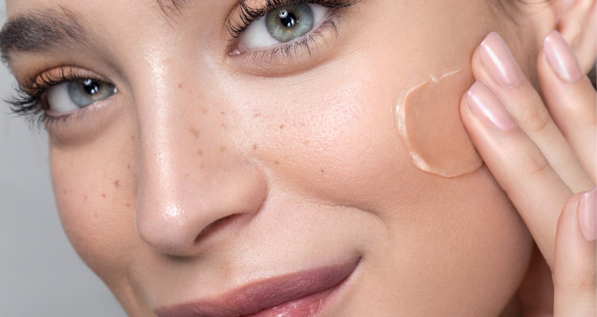 Cosmetic Services - white woman smiles while putting a clear cream on her cheeks