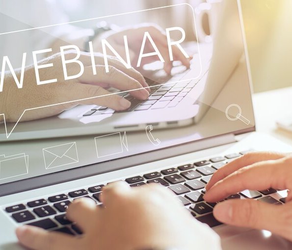 hands on laptop with the sign "webinar" on it