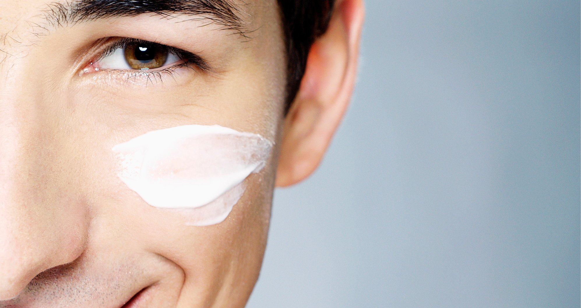 Cosmetic Services - the side of the face of a young man, he is having some lotion on his cheek