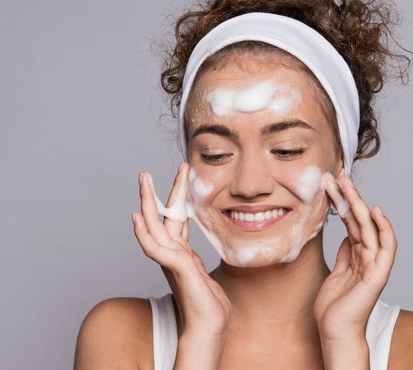 cosmetic webinar - young woman washing her face, she has foam on her face