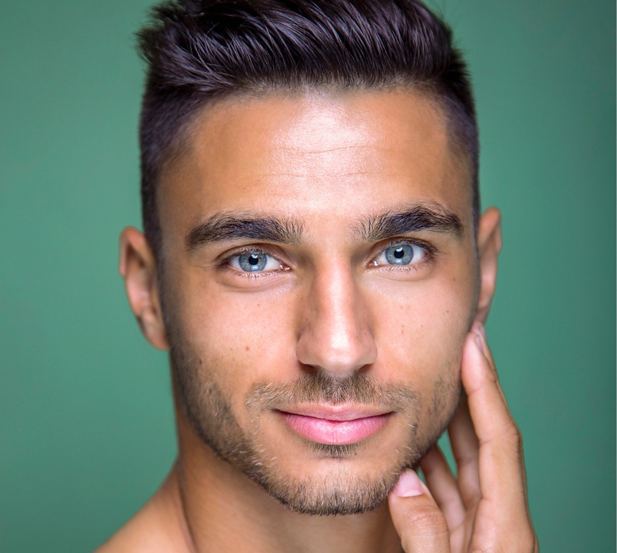 Cosmetic Services - face of a young man with blue eyes, he is holding his hand against his cheek