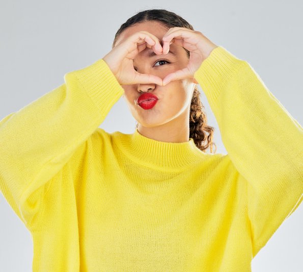 Rahn cosmetic news - woman in yellow jumper show heart sign with hands