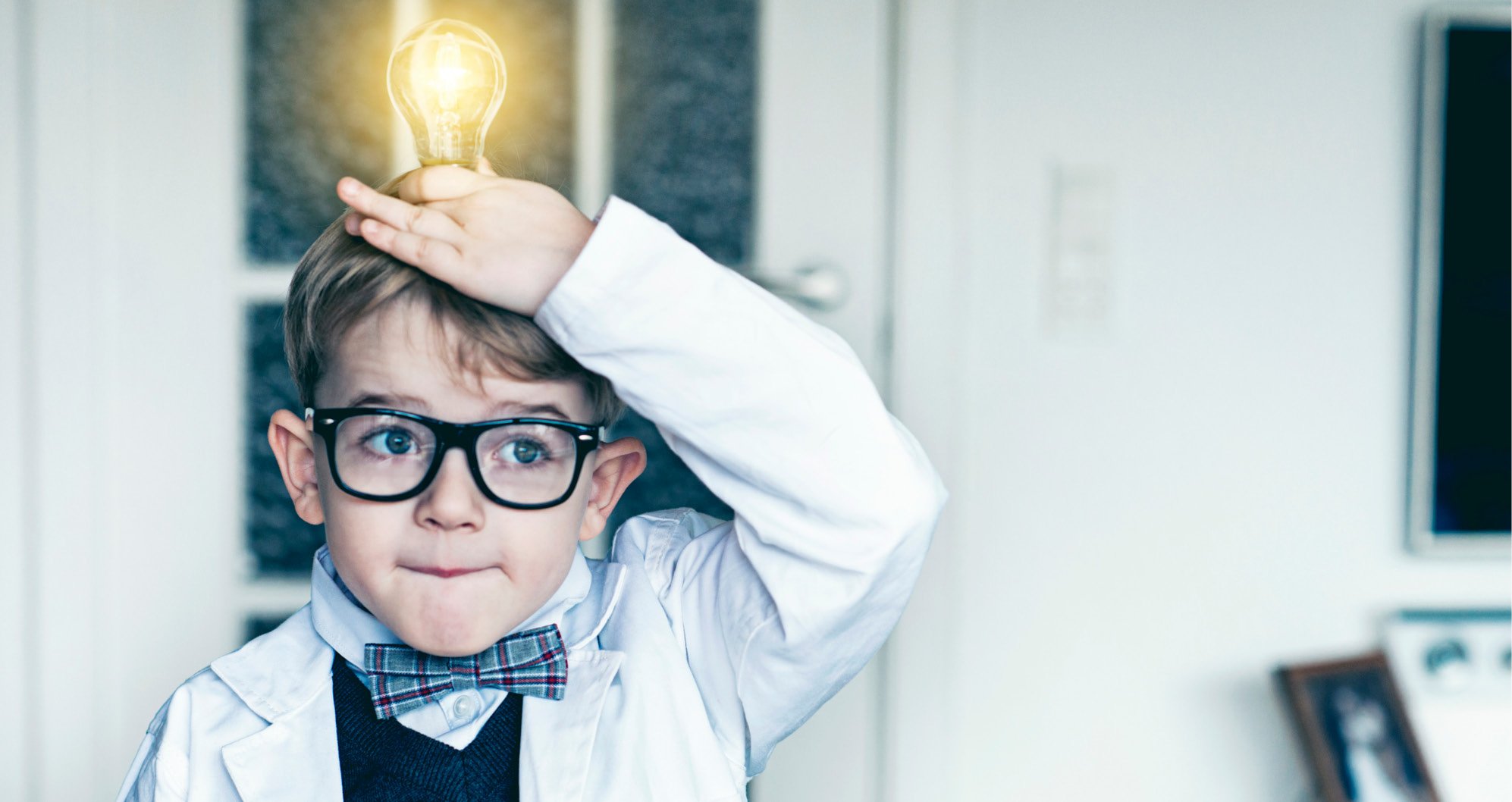 Cosmetic Services - a little boy with glasses and a white cape holding a light bulb over his head